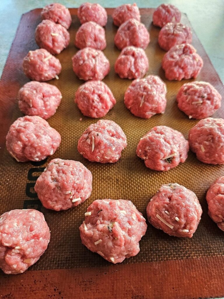 Homemade meatballs on a silicone matt ready to be baked.