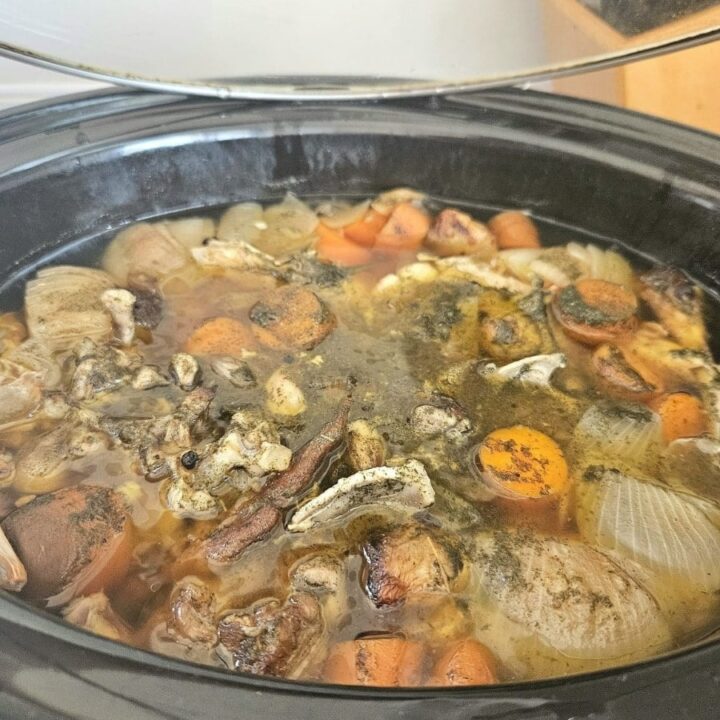 Bones and vegetable slow cooking in a crackpot to make bone broth.