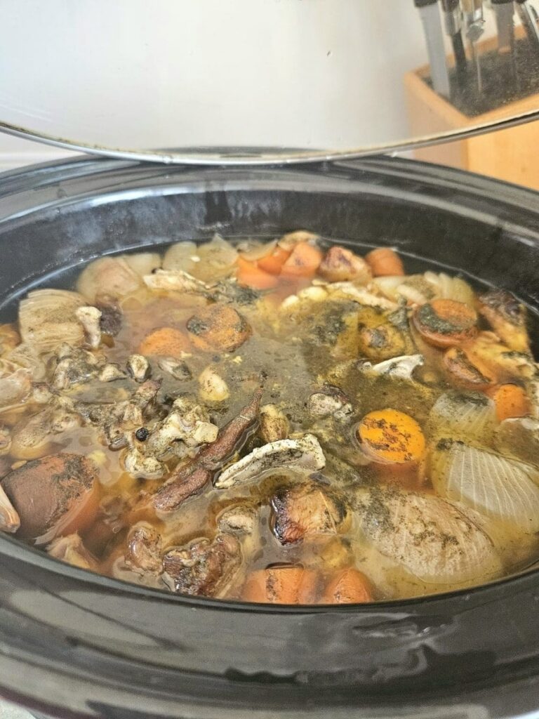 Bones and vegetable slow cooking in a crackpot to make bone broth.