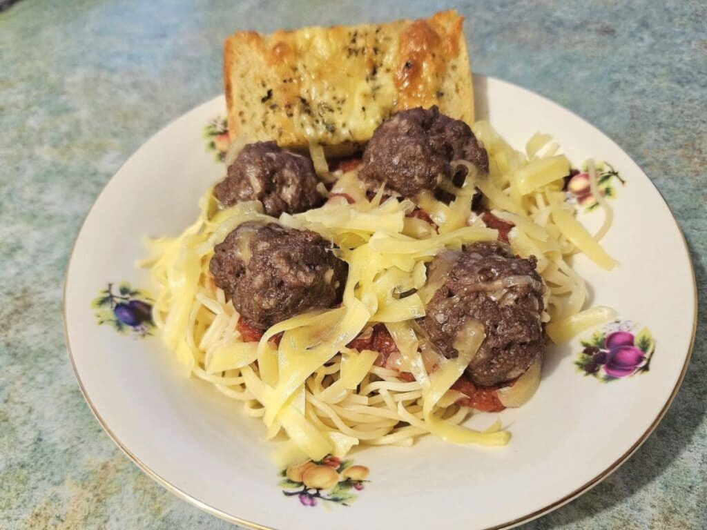 Homemade baked meatballs with spaghetti in a bowl.