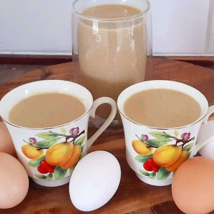 Creamy healthy homemade Eggnog recipe. Eggnog in cups with eggs on a cutting board