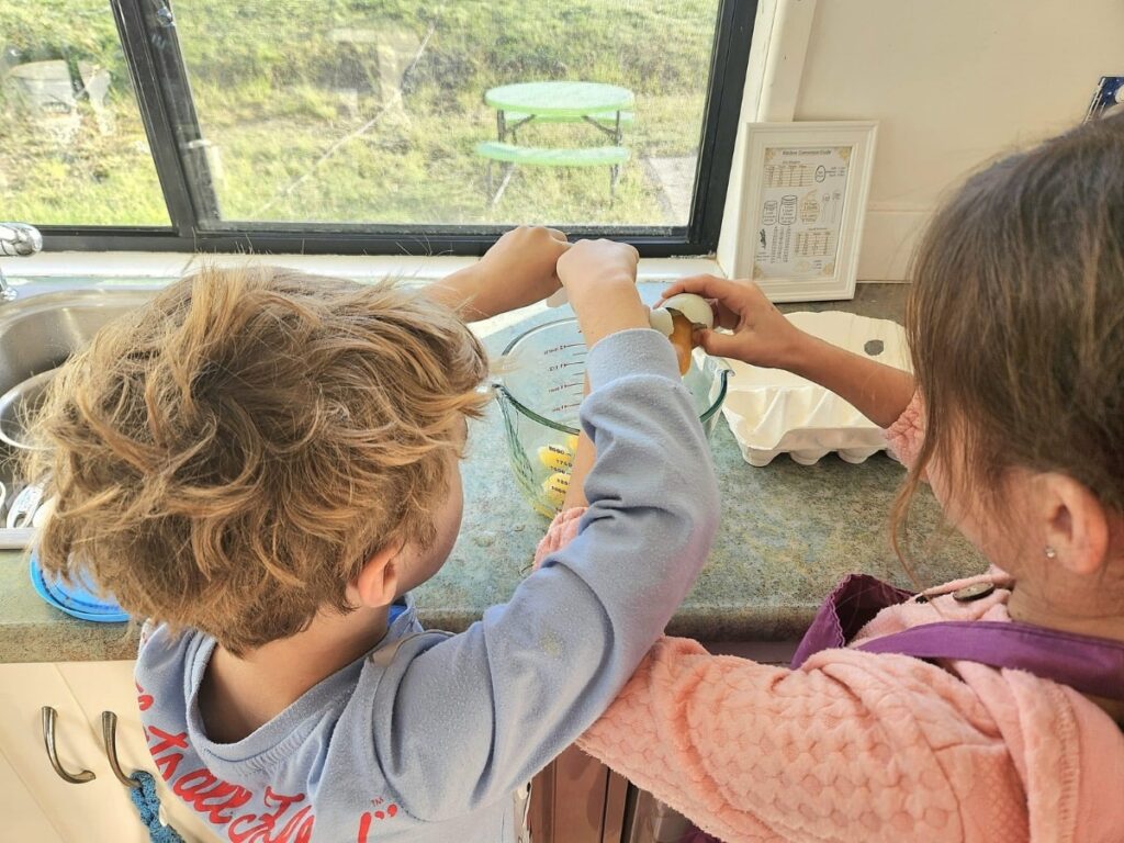 Kids helping to crack eggs in the kitchen.