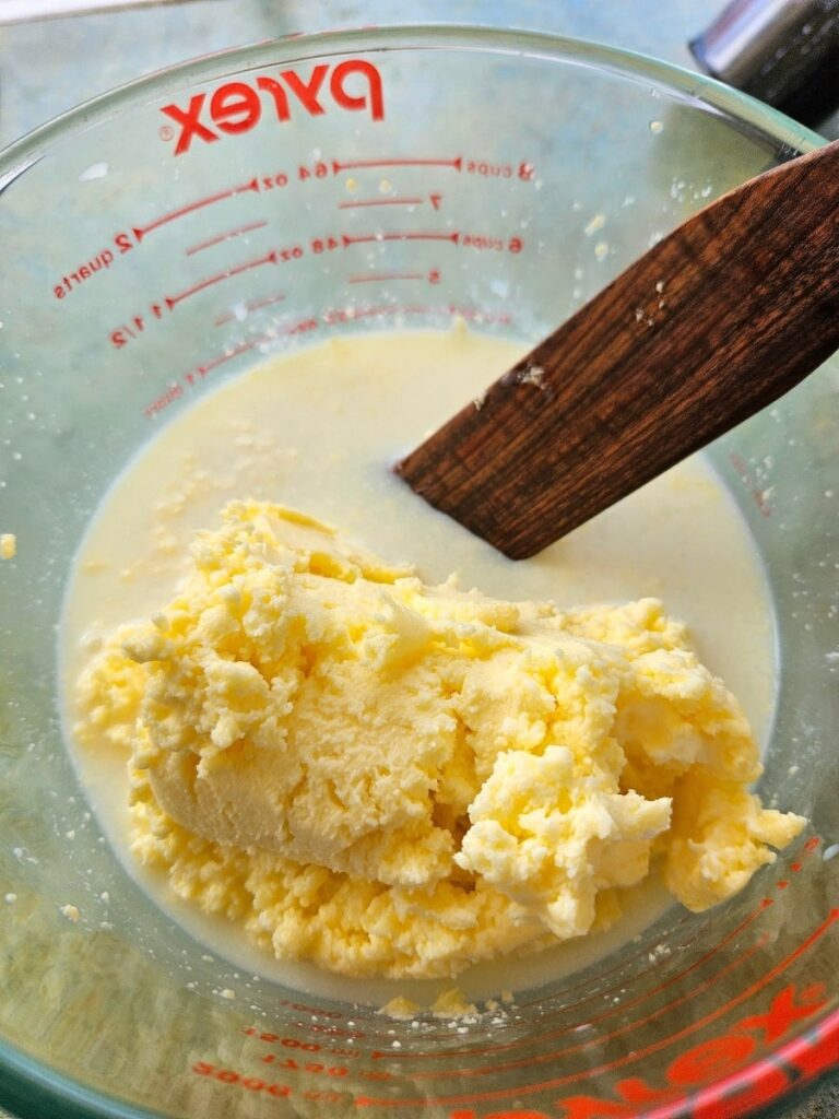 Straining the buttermilk from the butter in a pyrex jar.