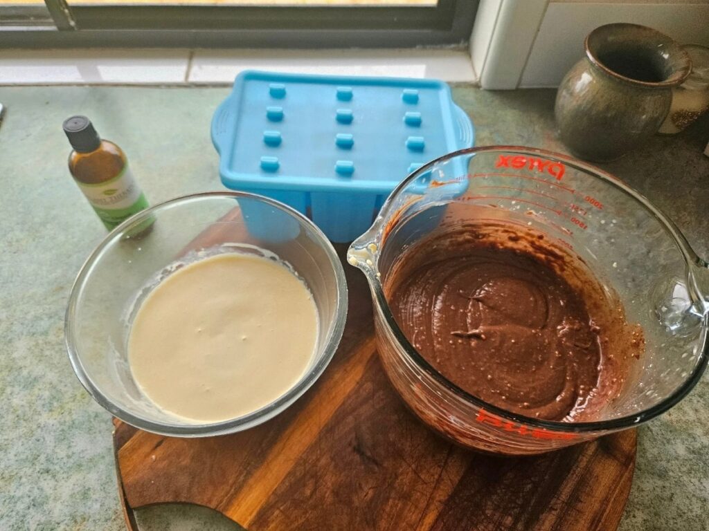 Mint chocolate cheesecake batter in 2 measuring cups ready to be poured into silicone moulds.