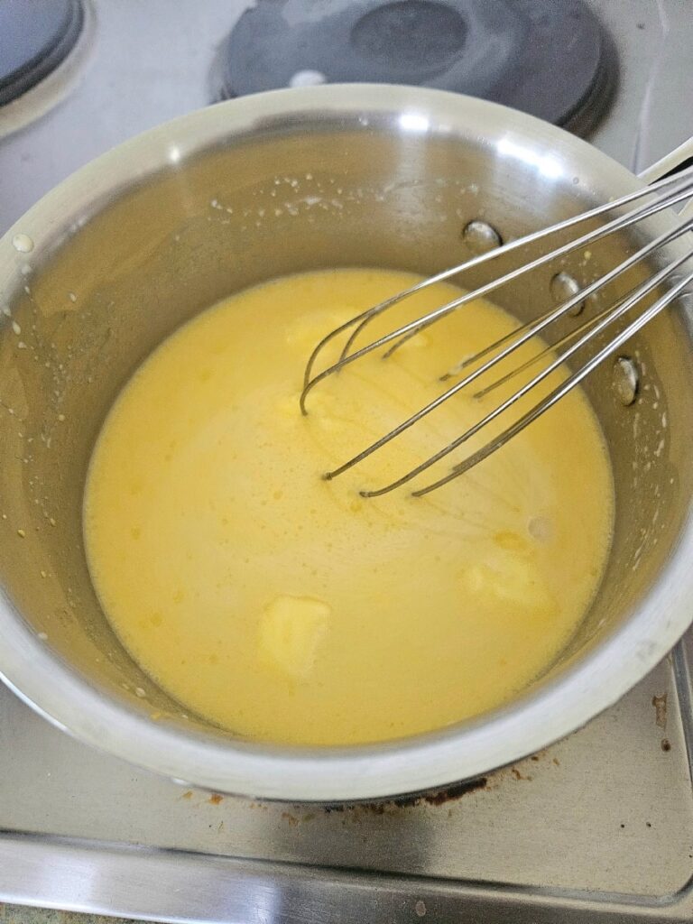 Mixing cheese sauce in a saucepan.