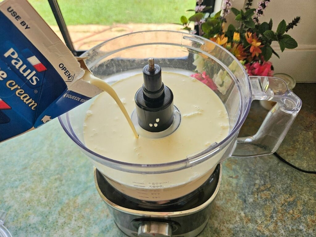 Pouring cream into a food processor to turn into butter.