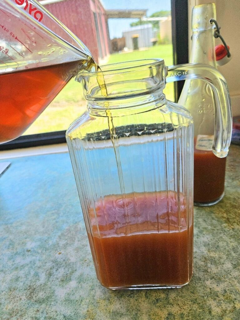 Pouring tea into peach syrup to make peach iced tea.