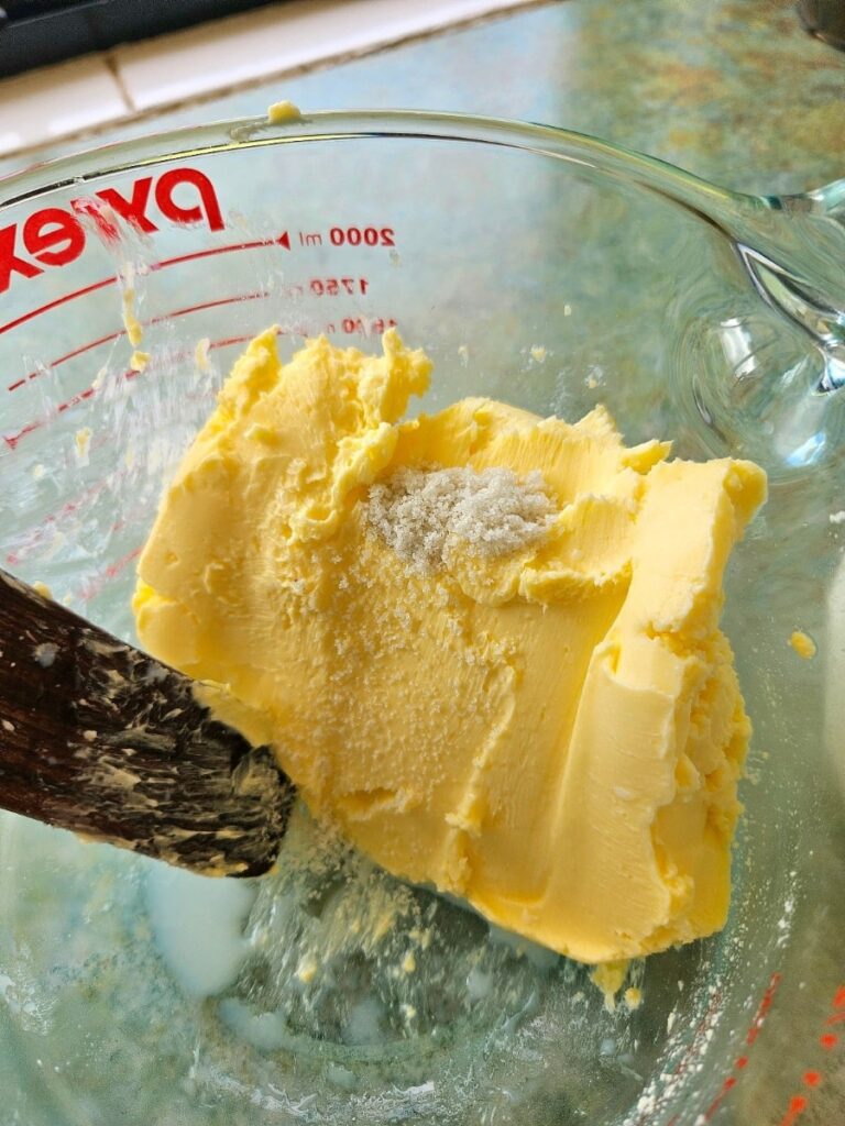 Mixing sea salt into homemade butter in a bowl.