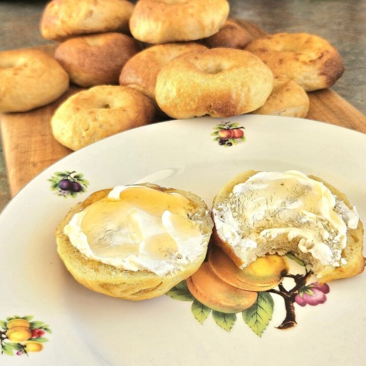 Homemade Sourdough bagels topped with cream cheese on a plate.