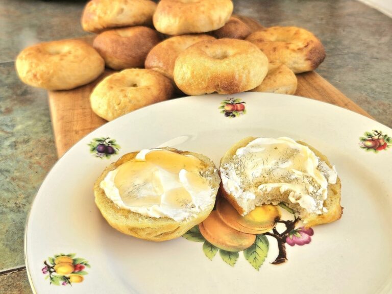 Homemade Sourdough bagels topped with cream cheese on a plate.