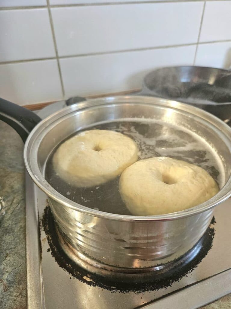 Sourdough Bagels boiling in a pot.