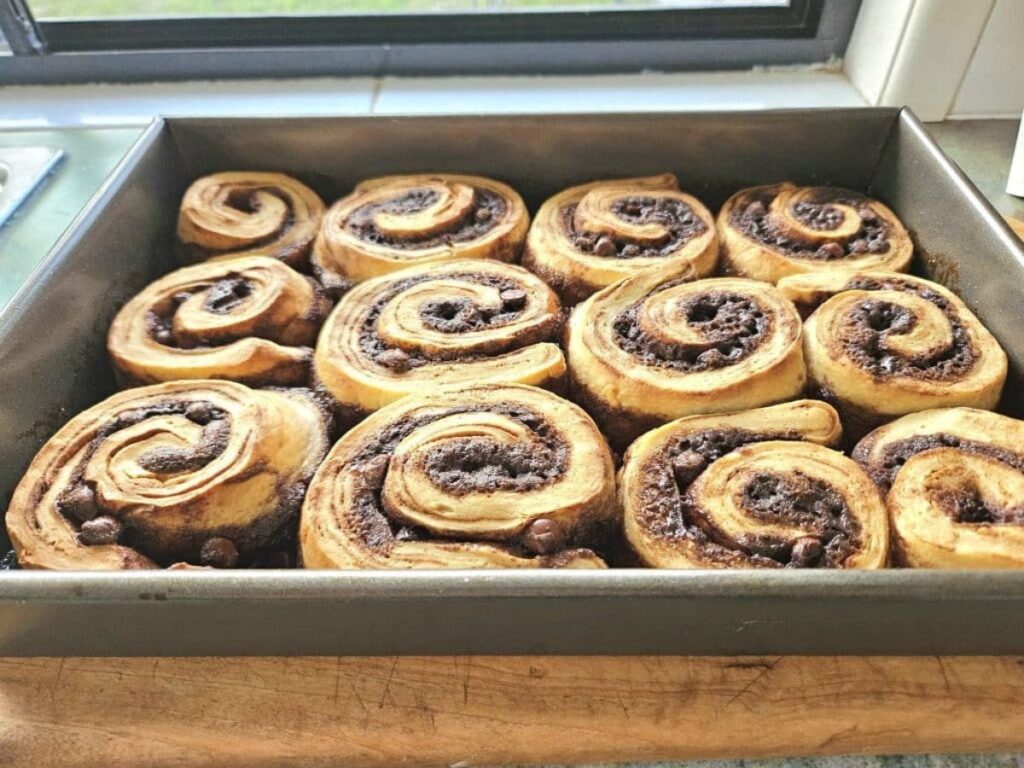 Freshly baked sourdough cinnamon rolls in a tray.