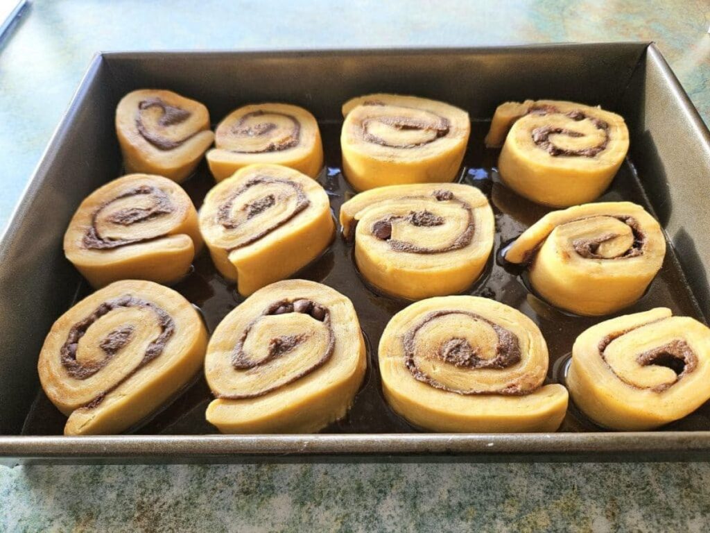 Sliced cinnamon rolls in a baking tray ready to be baked.