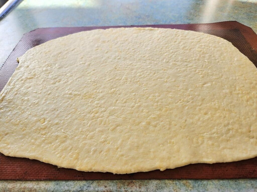 Cheesy sourdough cracker flattened down ready for cutting.