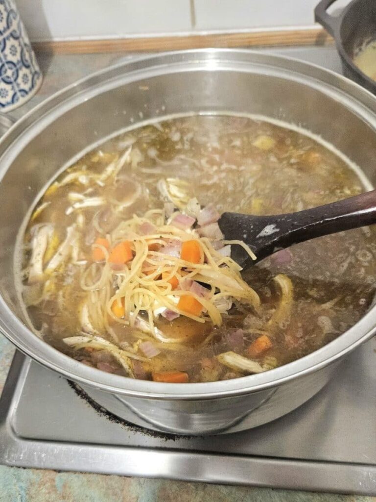 Simmering chicken noodle soup in a pot.