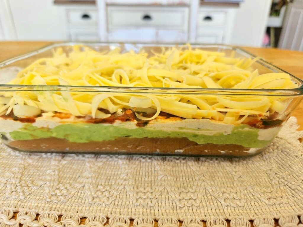 Healthy homemade 5 layer bean dip in an container on a table.