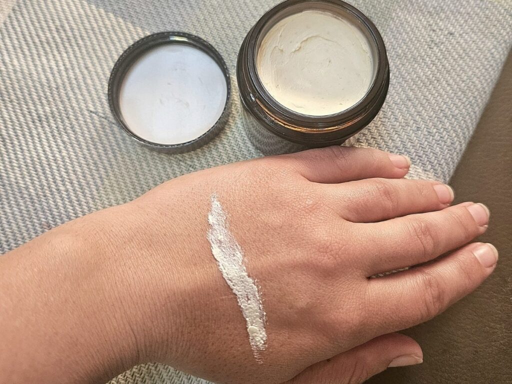 Homemade sunscreen in a jar and on a hand.