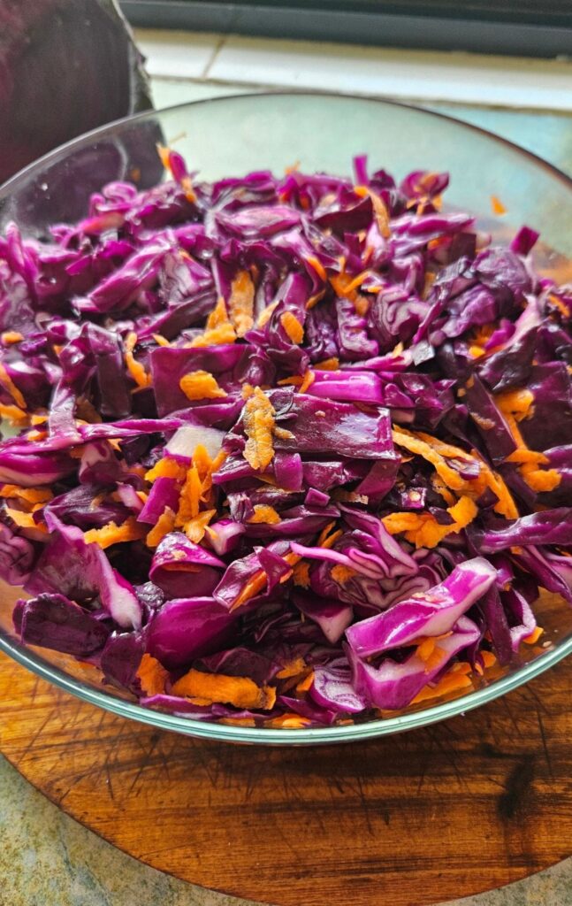 Shredded cabbage and carrots in a bowl to make sauerkraut.