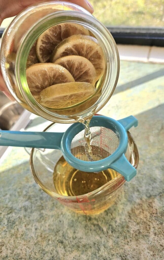 Sieving citrus from homemade vinegar spray in a jar.