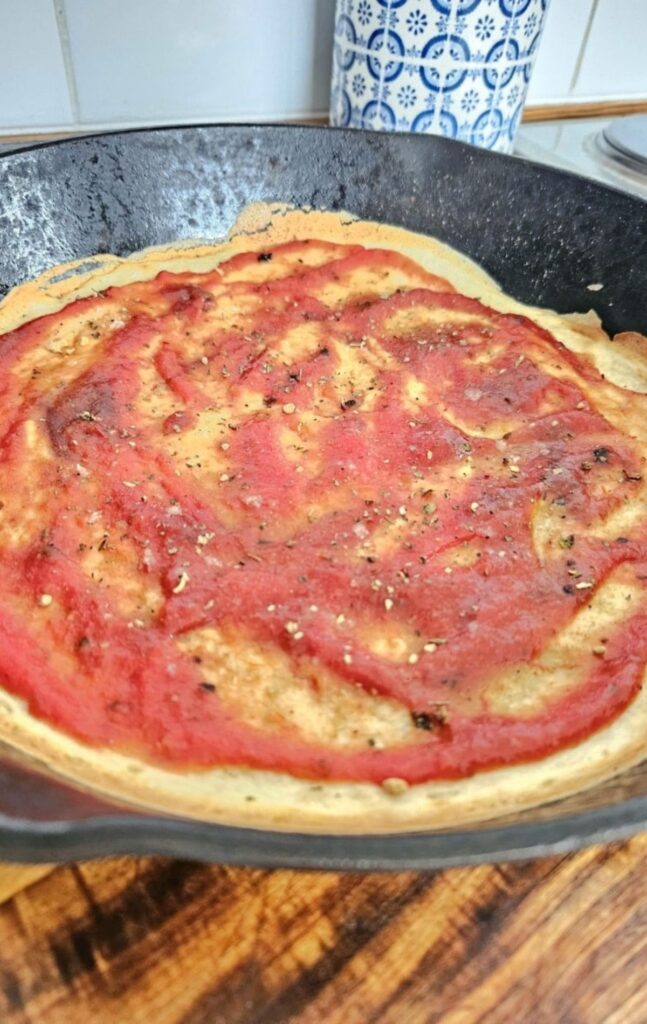 Adding pizza sauce to sourdough discard pizza crust