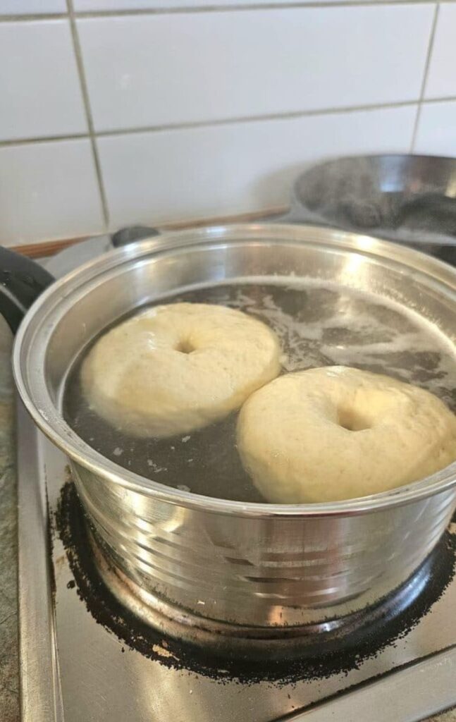 Sourdough Bagels in a boiling pot of water cooking.