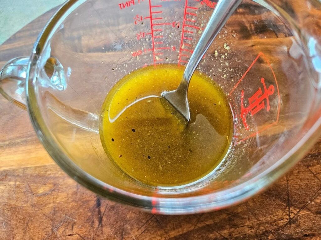 Balsamic vinegrette dressing ingredients in a glass pyrex measuring cup.