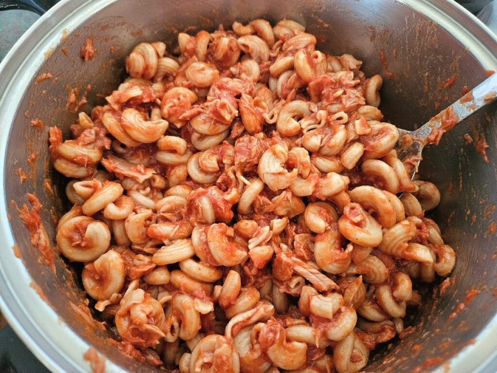 Cooking pasta with tuna and sauce in a large pot.