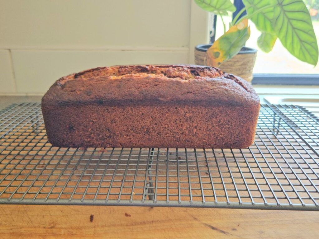 Homemamde banana bread resting on a cooling rack.