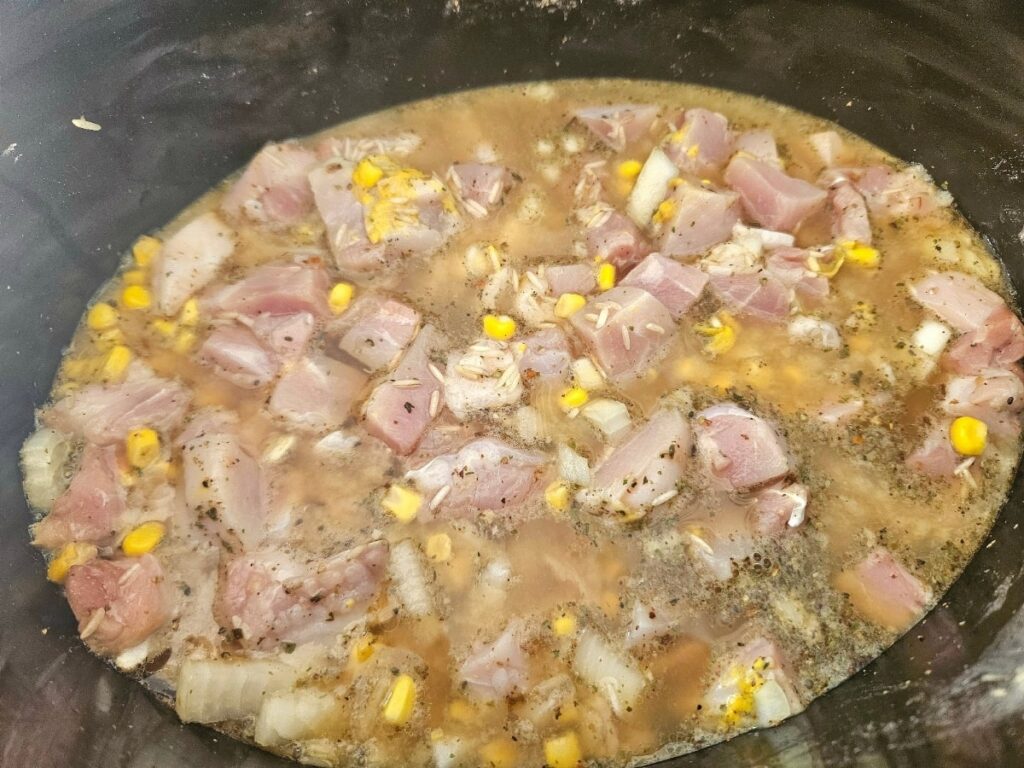 All ingredients poured into a slow cooker for chicken broccoli and rice.