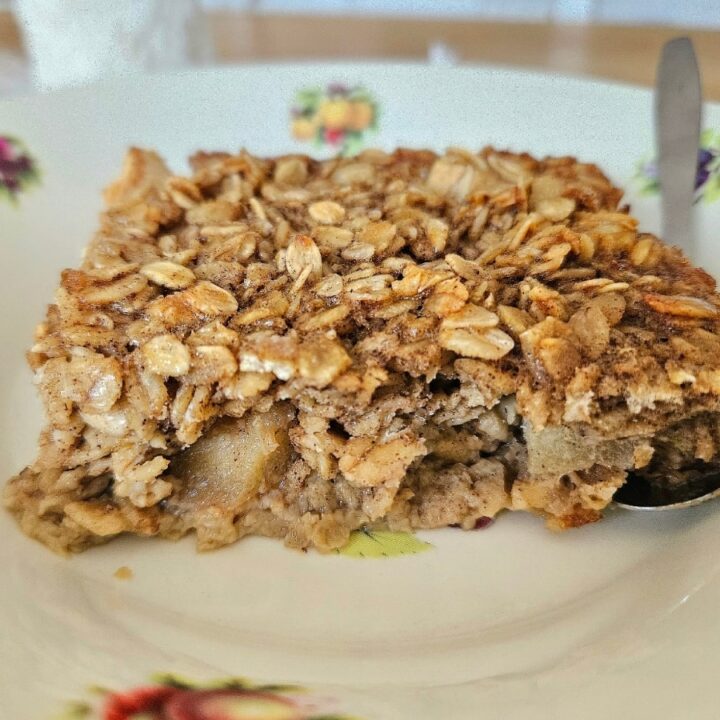 Baked apple and orange oatmeal in a bowl with spoon.