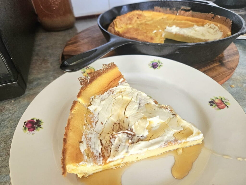 German pancake topped with cream cheese and honey on a plate.