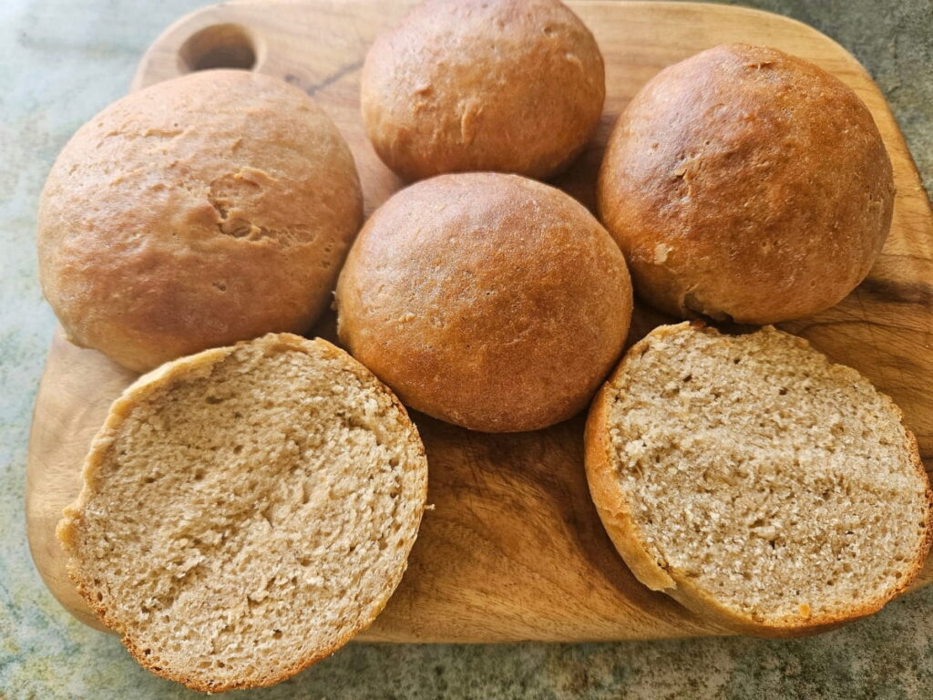 Hamburger buns on a cutting board. One cut open.