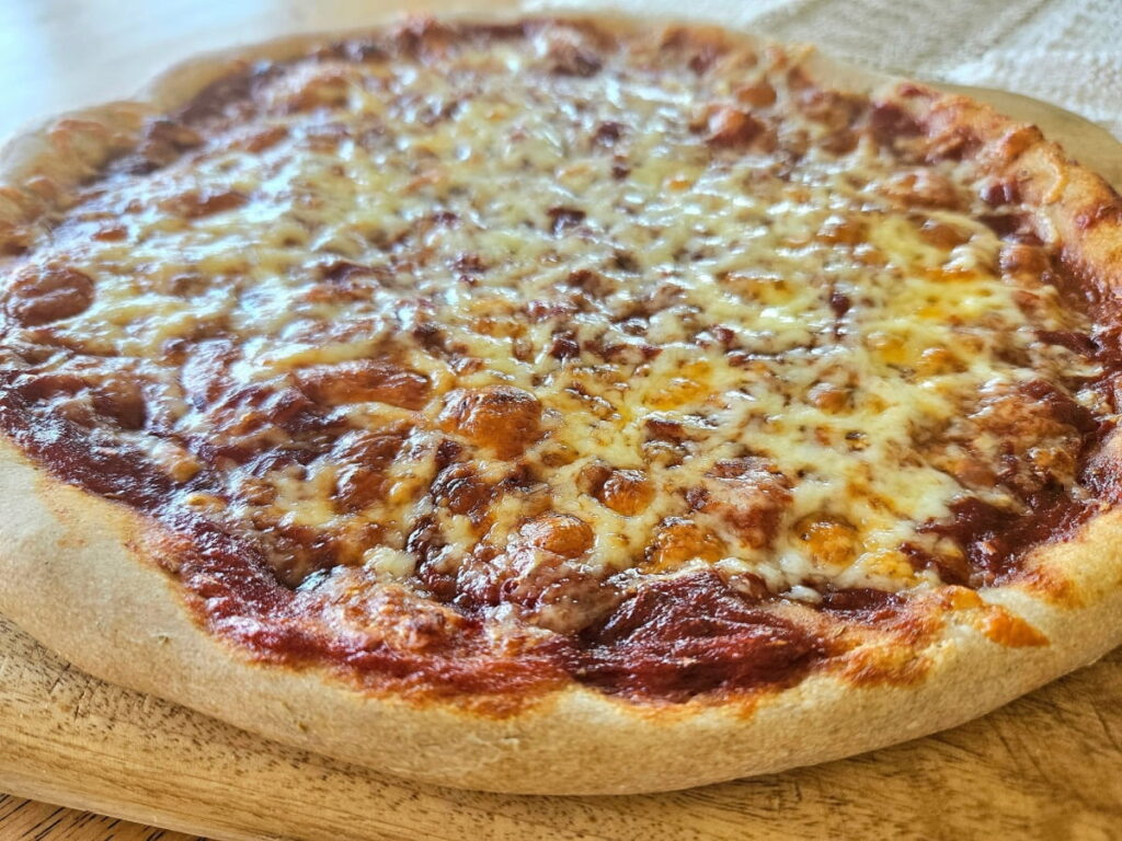 Baked sourdough cheese pizza on a cutting board.