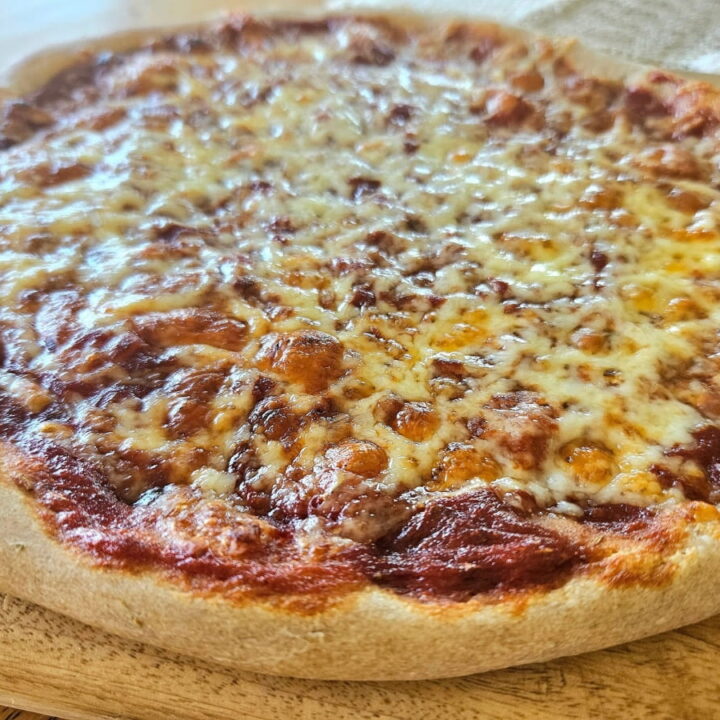 Baked sourdough cheese pizza on a cutting board.