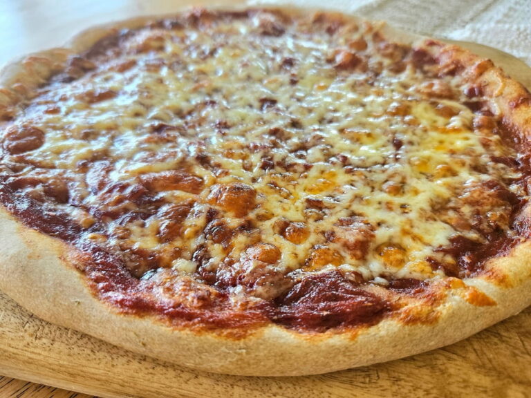 Baked sourdough cheese pizza on a cutting board.