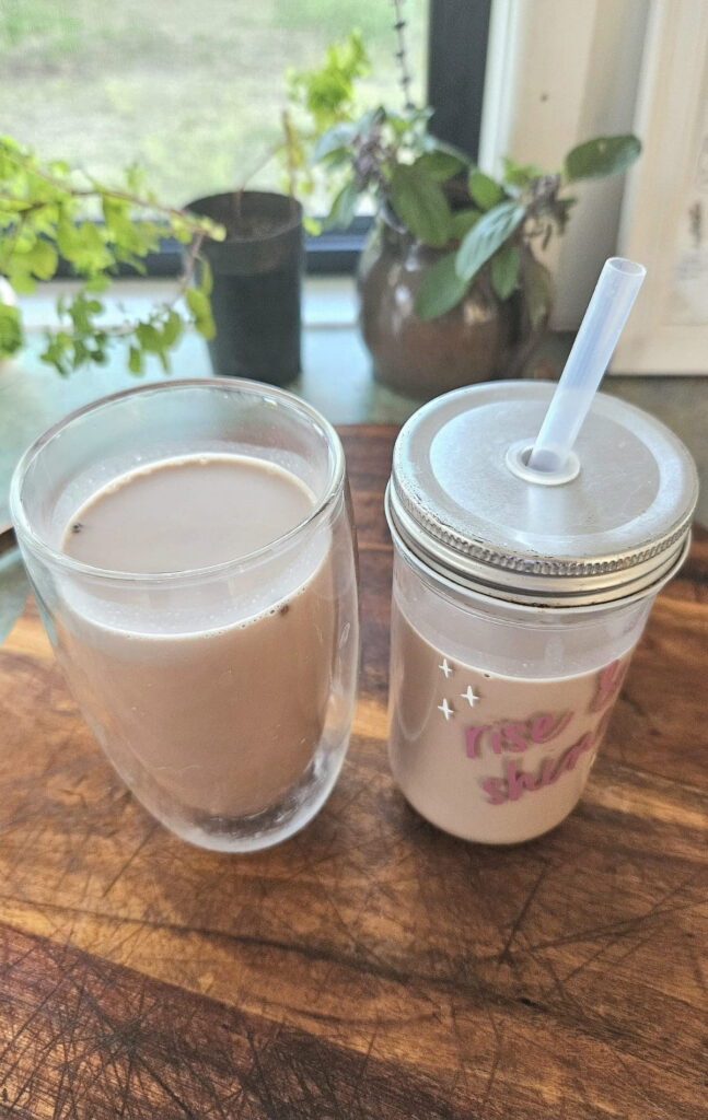 Chocolate milk poured into glass cups on a bench top.