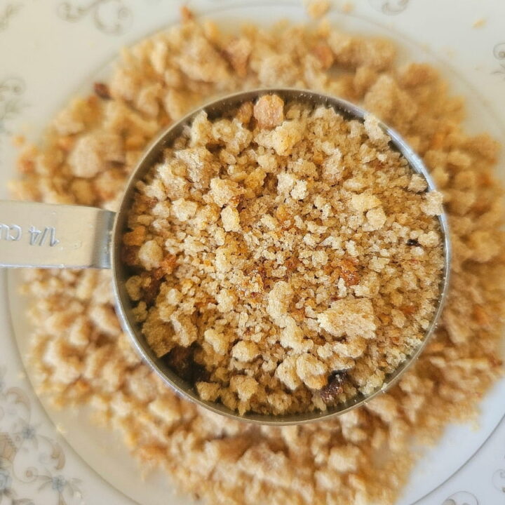 Breadcrumbs in a measuring cup on a plate.