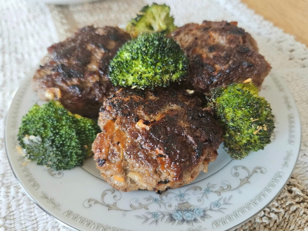 Homemade rissoles on a plate with broccoli.
