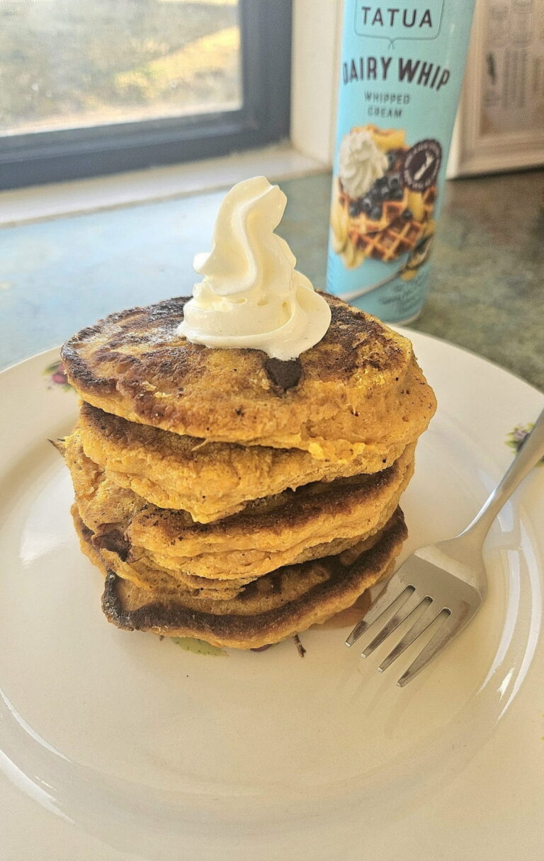 Chocolate chip pumpkin pancakes stacked on top of each other on a plate.