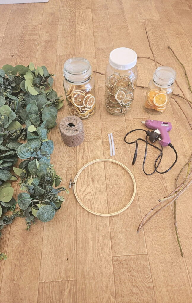 Wreath supplies, hot glue gun, dried citrus, faux garland and sweet potato vine.