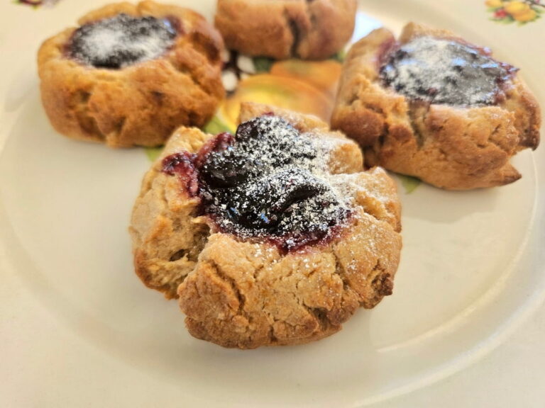 Lemon berry thumbprint cookies on a plate with icing sugar.