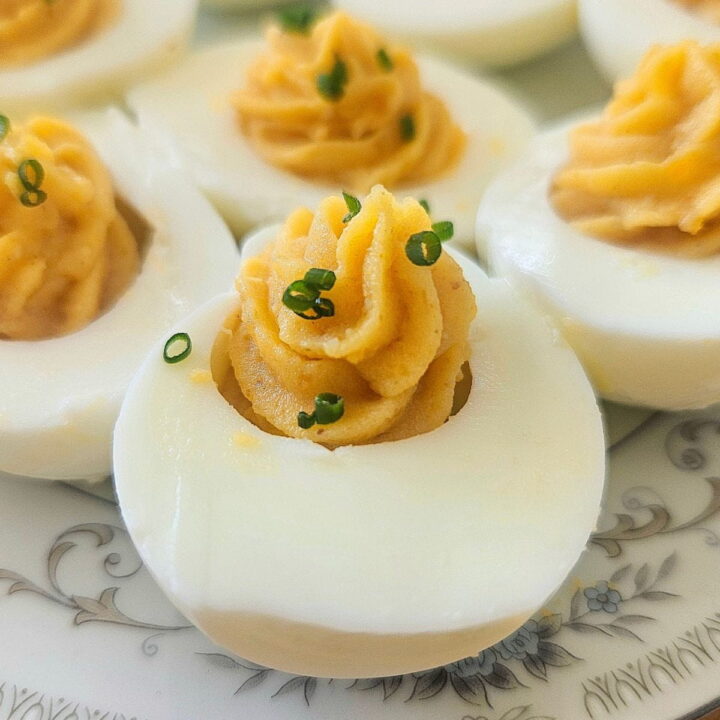 Curried deviled eggs sliced on a plate.