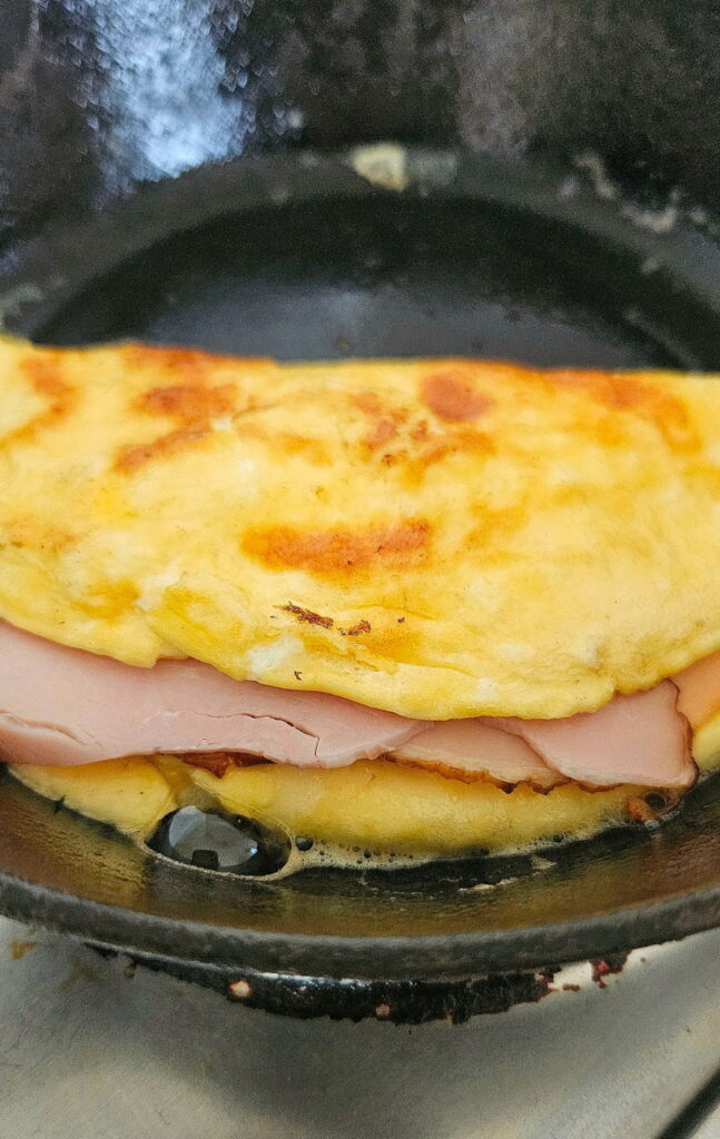 Simple omelette cooking in cast iron pan.